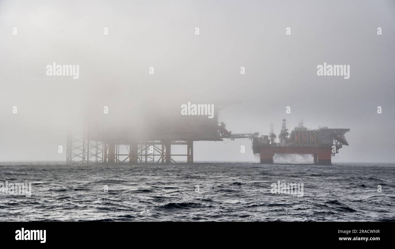 Offshore crude oil production installation covered in fog in the ocean. Jack up drilling rig, semi submersible platform covered in fog in the sea. Stock Photo