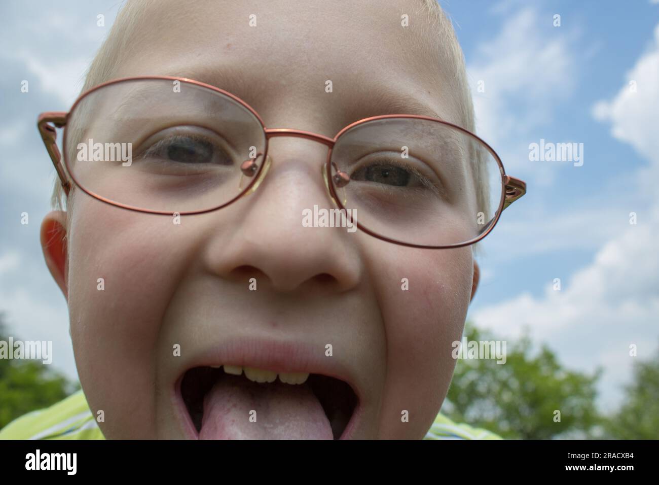 a fun little boy in the glasses shows a tongue Stock Photo