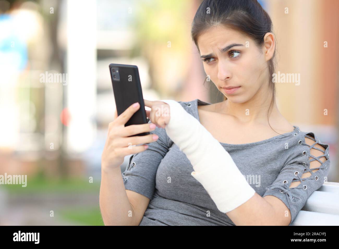 Suspicious convalescent girl checking phone content in the street Stock Photo
