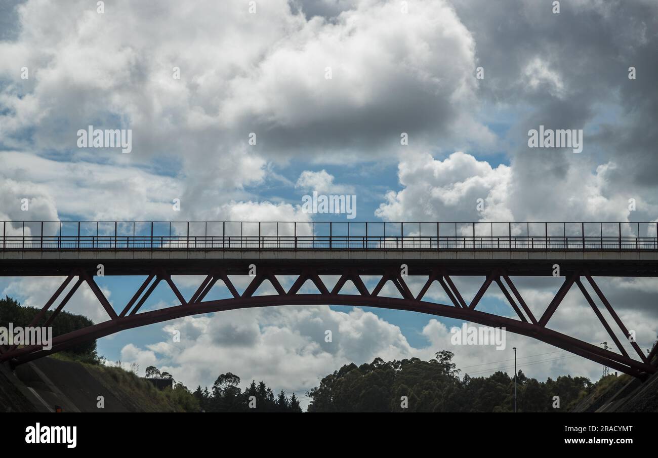 Image composed of a bridge in the foreground in backlight and castellated clouds contrasting with the blue sky in the background. Stock Photo