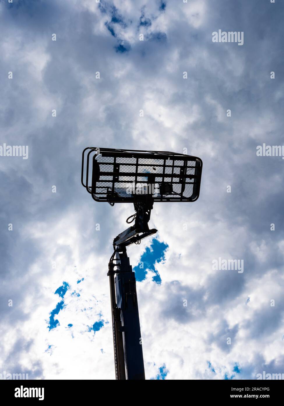 A cherry picker (an aerial work platform or bucket truck) against a dramatic cloudy sky Stock Photo