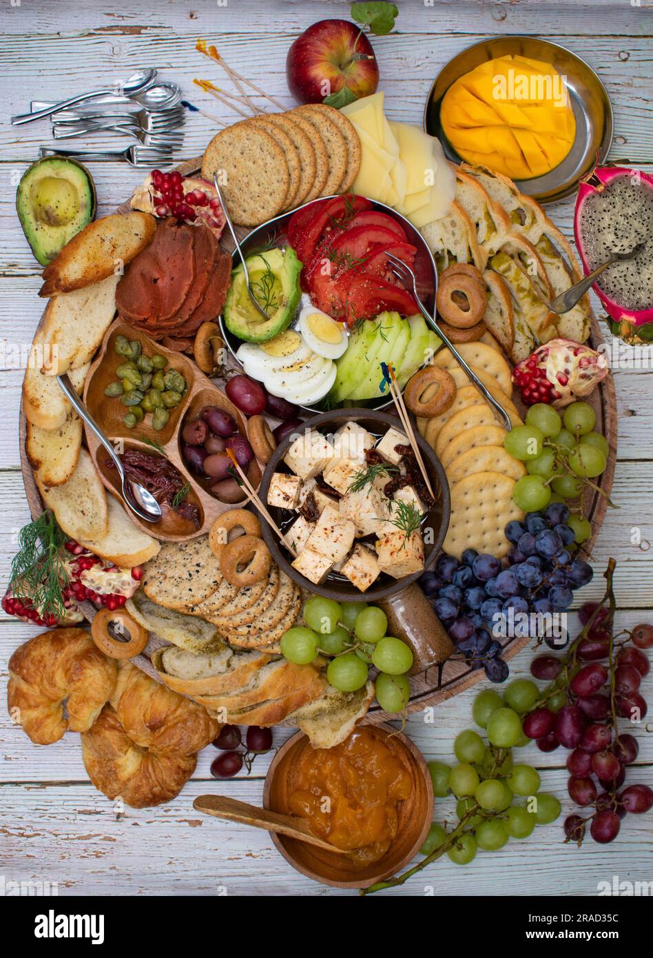 Appetizer board with crackers, cheese, vegetables and grapes Stock Photo