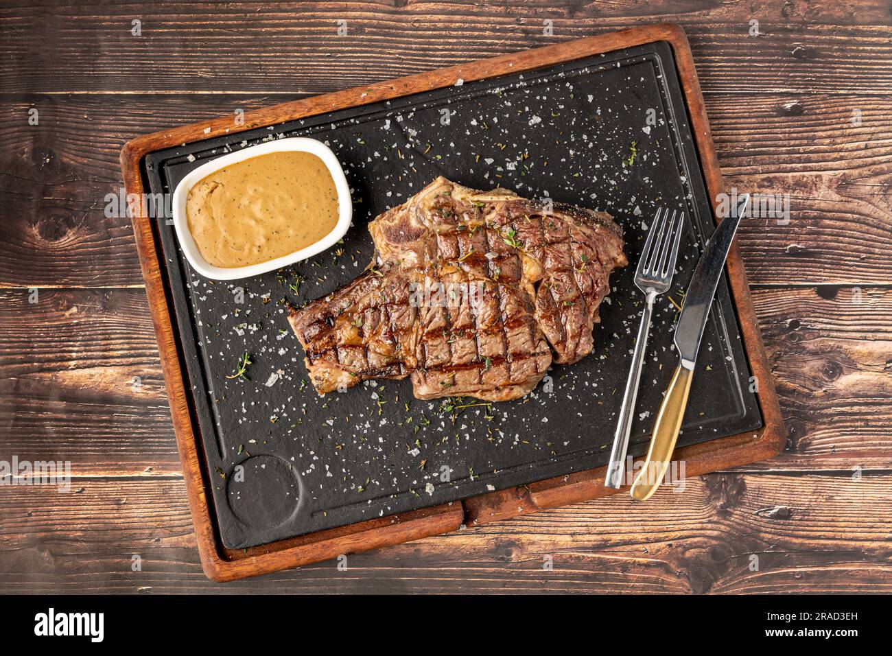 Grilled tomahawk steak on stone cutting board in steakhouse restaurant Stock Photo