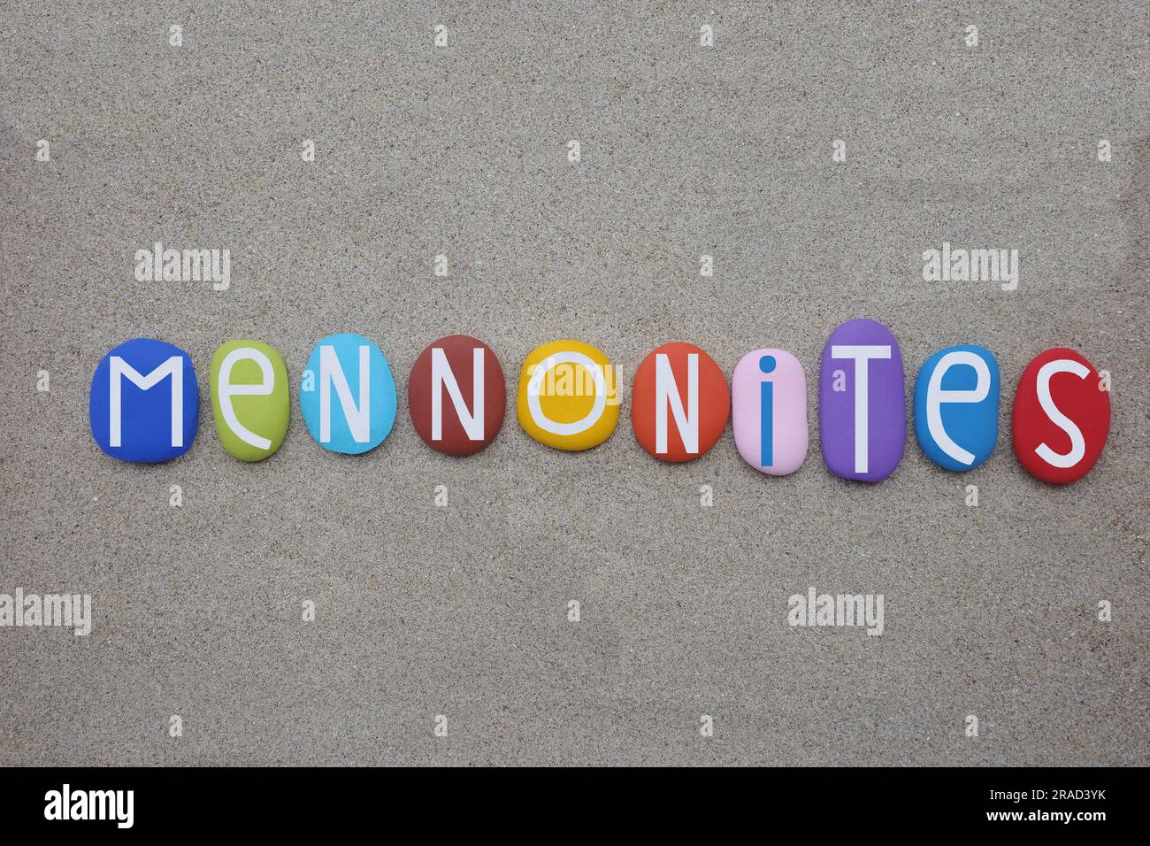 Mennonites, groups of Anabaptist Christian church communities of denominations, creative text composed with multi colored stone letters on the sand Stock Photo