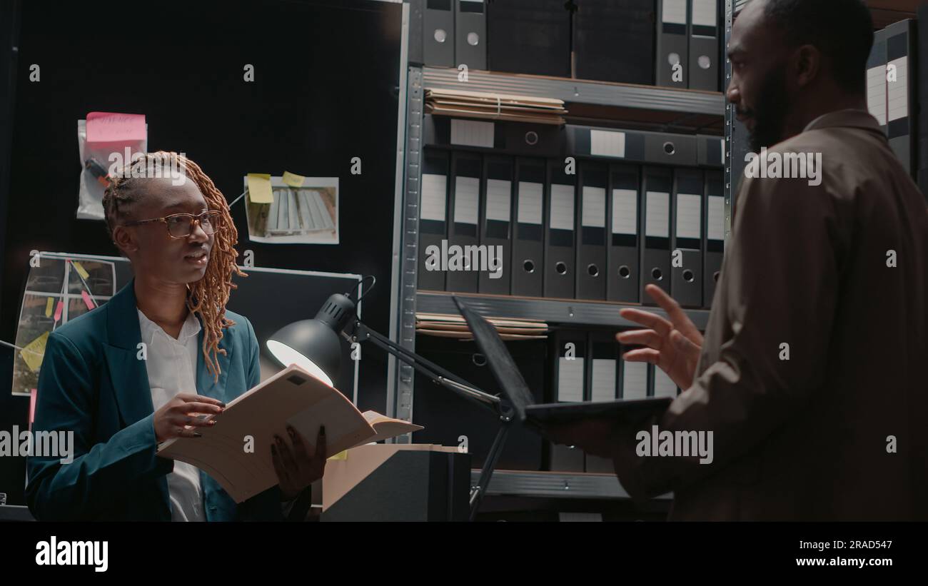 Police office assistant reading case file for detective, doing teamwork