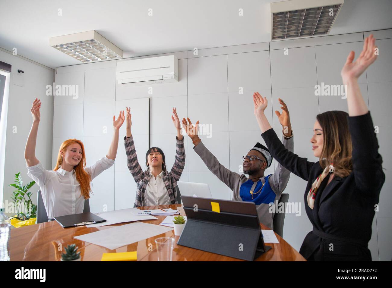 A group of business people with their hands raised to the sky, carefree and relax in the office Stock Photo