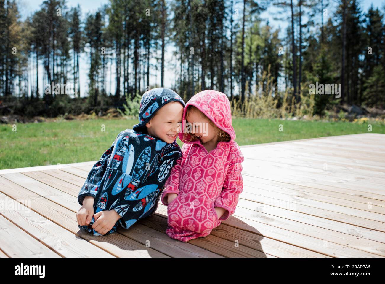 girl and boy sat close laughing together in the garden at home Stock Photo