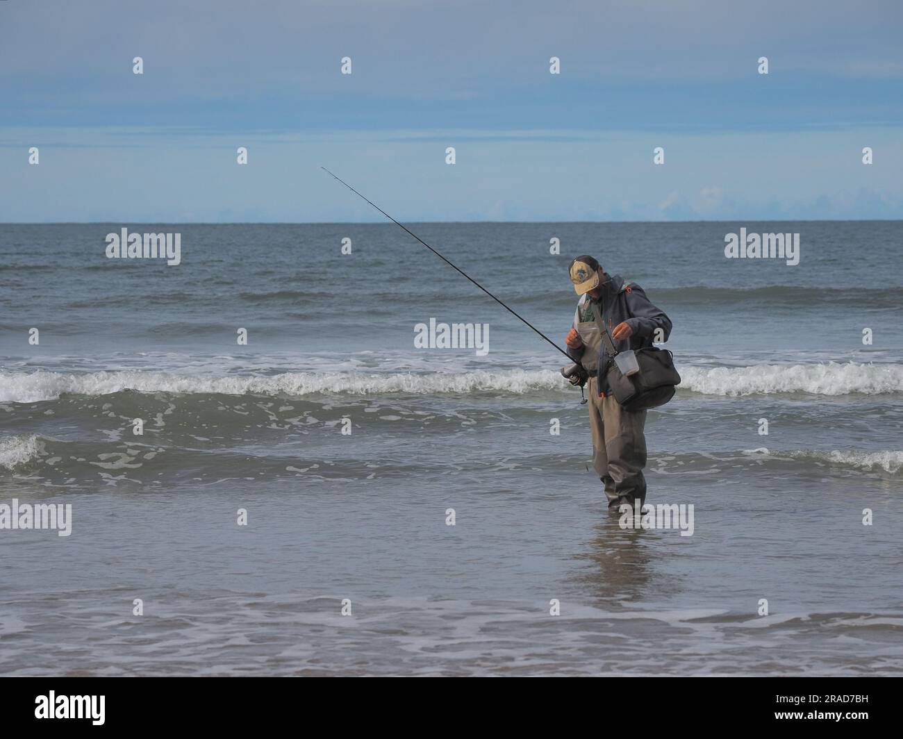 Fisherman baiting hook on Rhossili beach, Rhossili Bay, Gower Peninsula, Wales Stock Photo