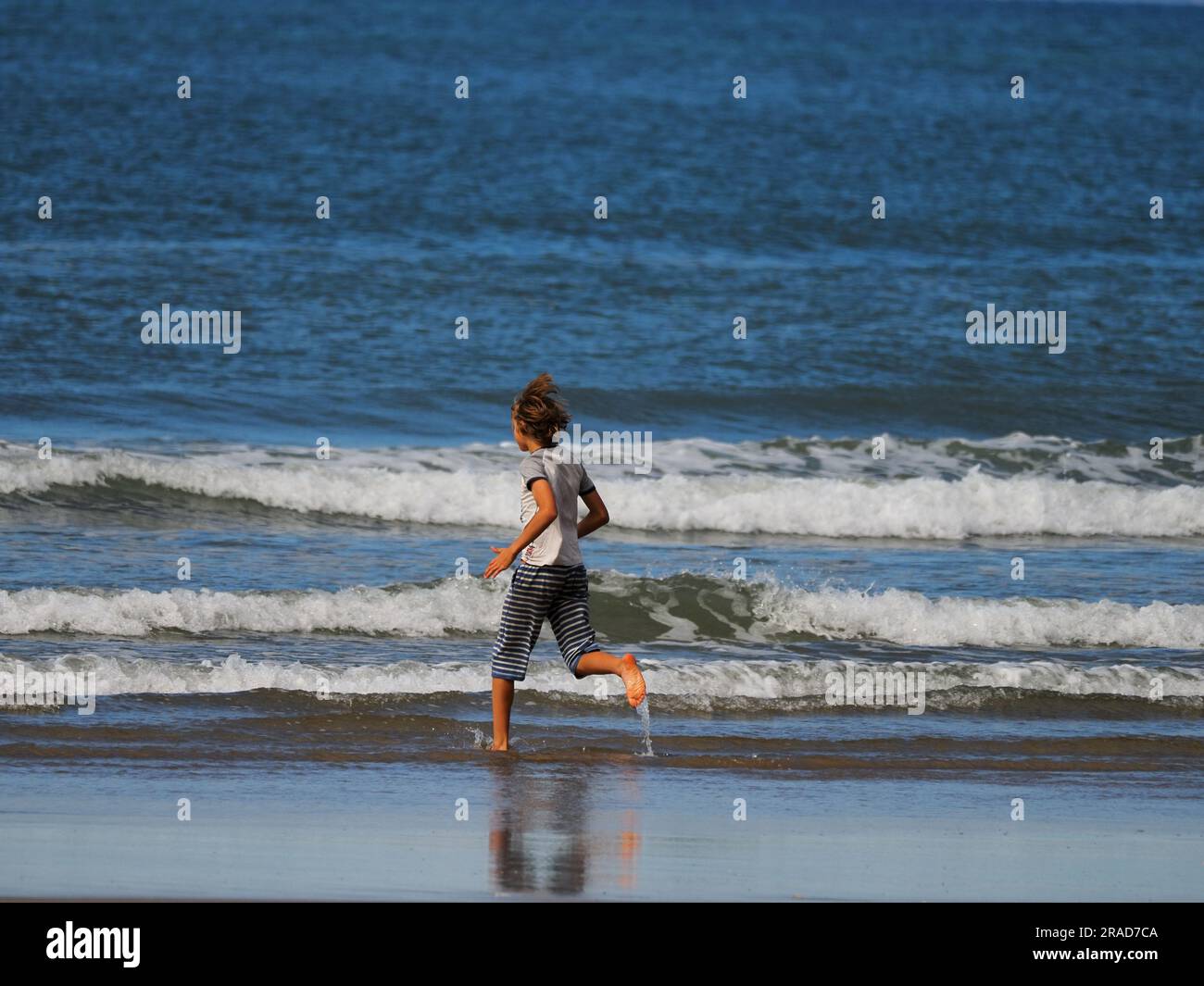 Boy running on beach, Rhossili Bay, Gower Peninsula, Wales Stock Photo