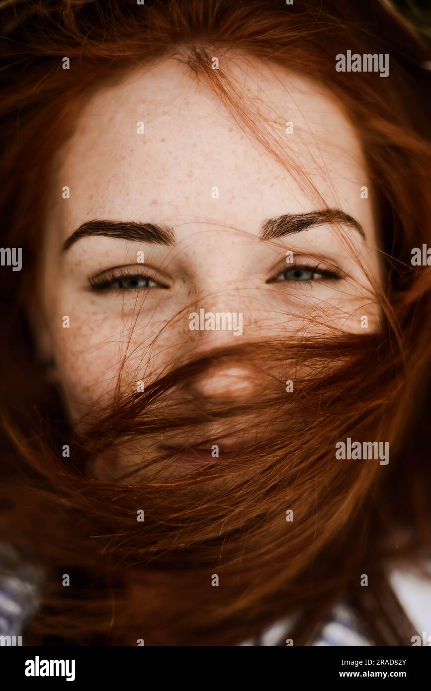 Close-up portrait of teenage girl with red head lying on grassy Stock Photo