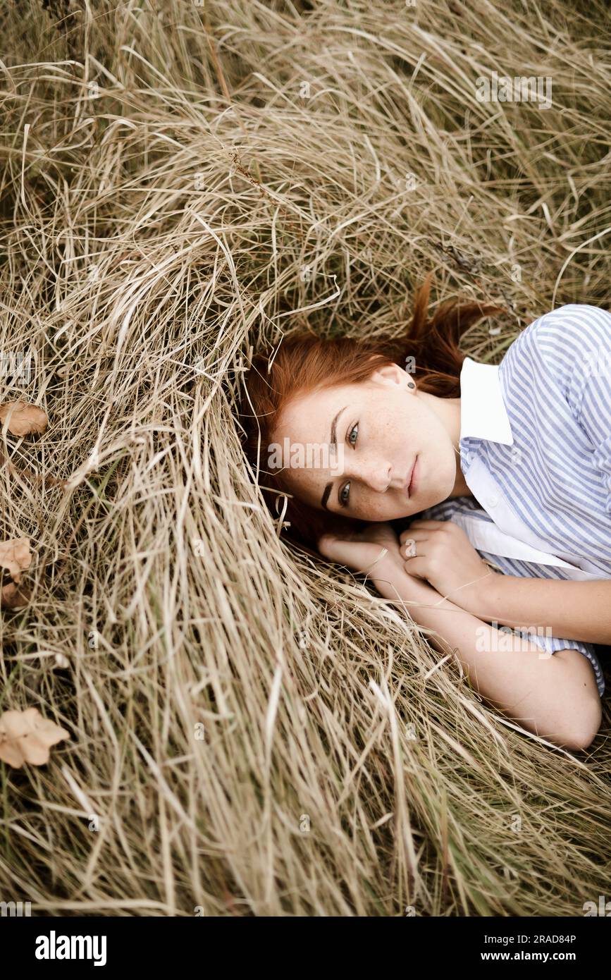 Close-up portrait of teenage girl with red head lying on grassy Stock Photo