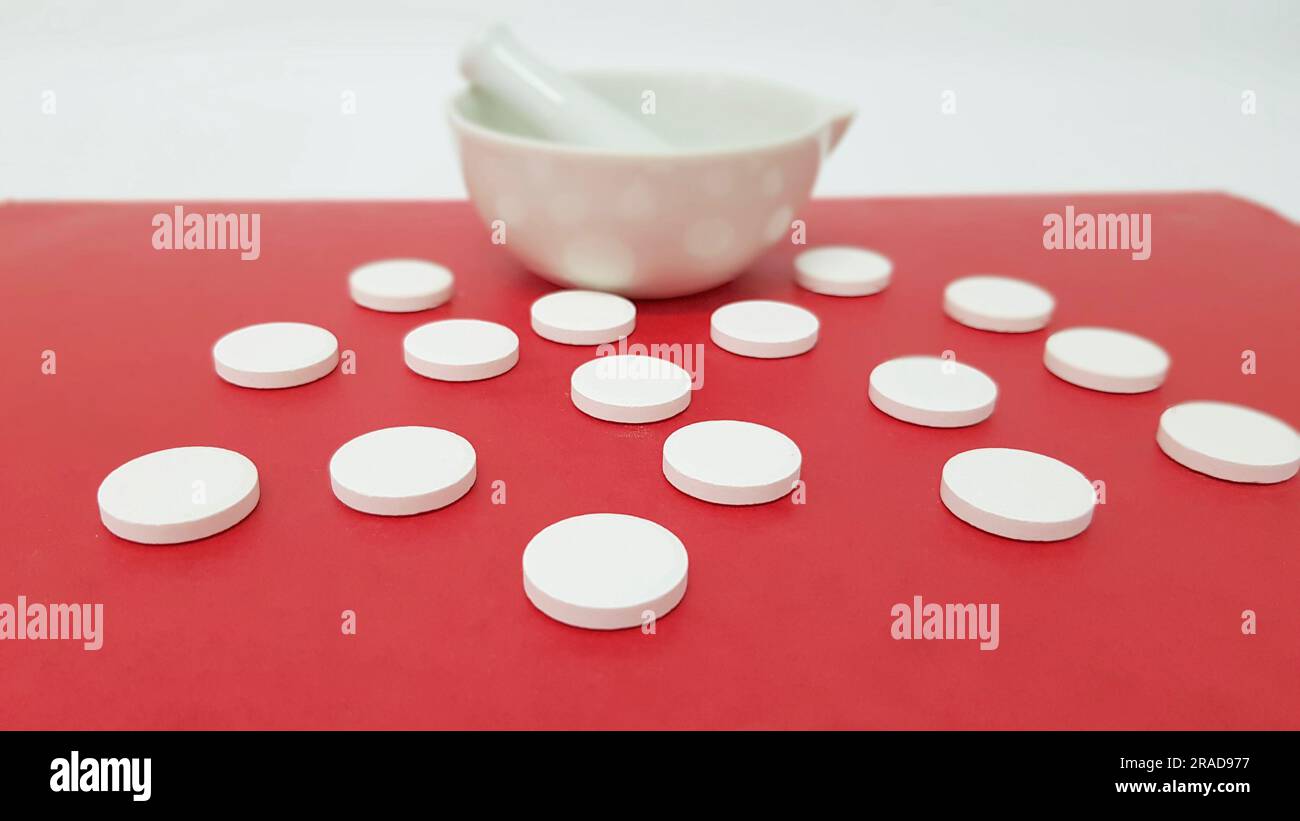 Effervescent tablets and mortar in red background Stock Photo