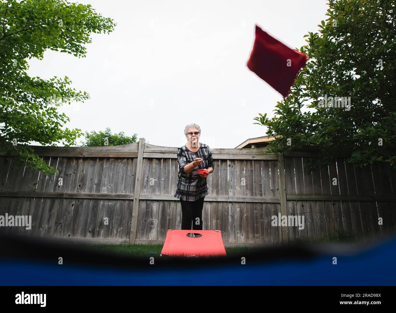 Mature woman throwing bean bag during corn hole game shot from below ...