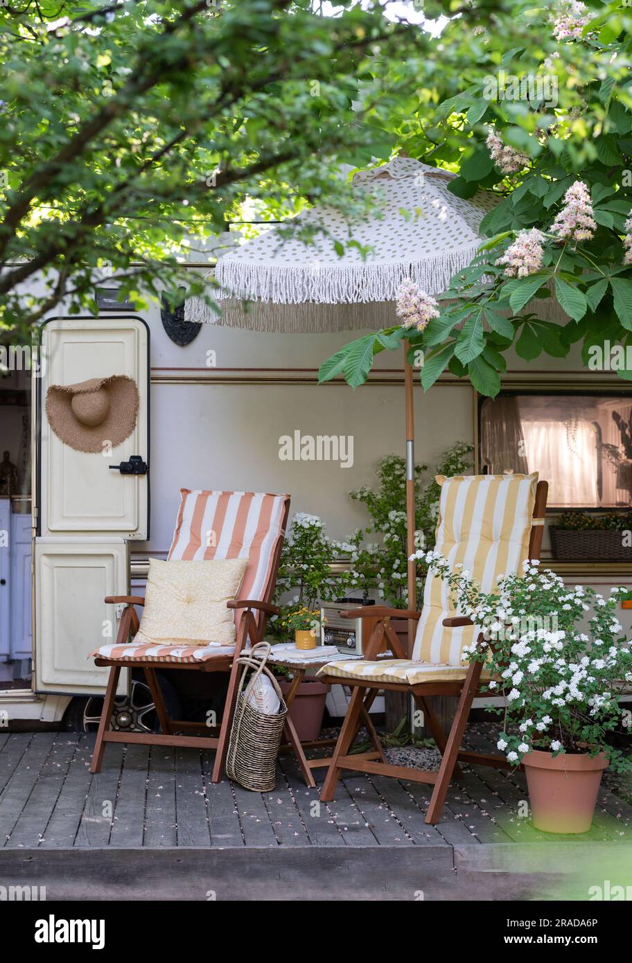 Terrace mobile home in spring, mobile home, green leaves, sun lounger with blanket, flowerpot, table and bonfire Stock Photo