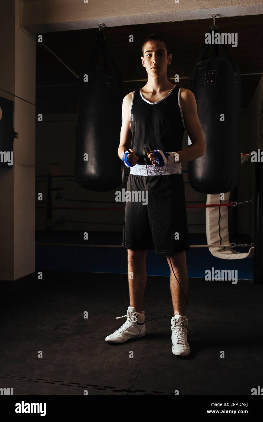 Young boxer standing with jump rope to start workout in gym. Stock Photo