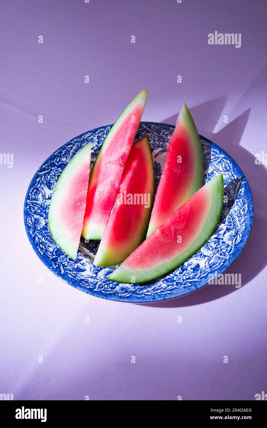 Patterned plate with slices of a fresh watermelon on pink table-cloth Stock Photo