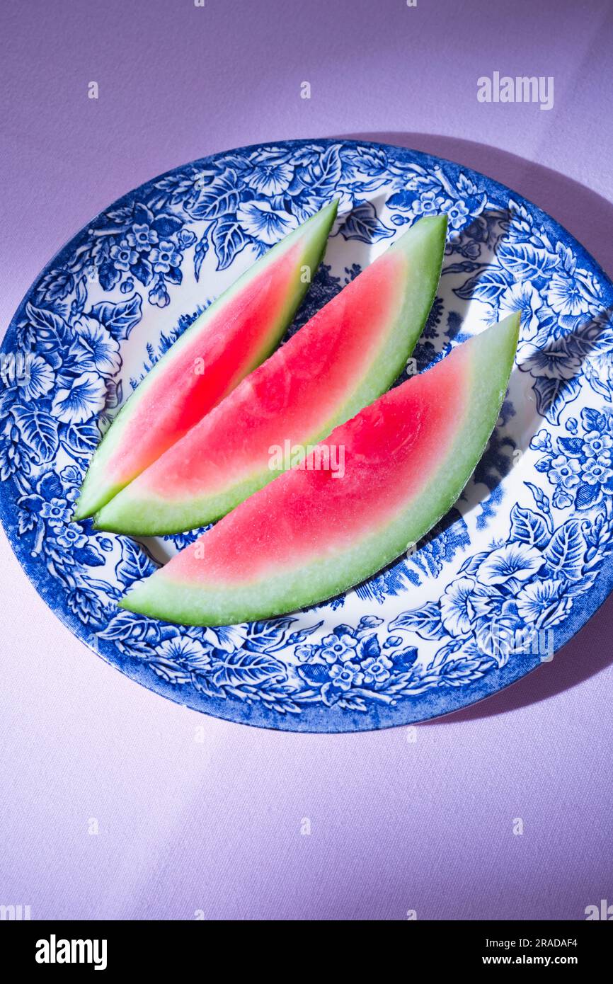 Patterned plate with slices of a fresh watermelon on pink table-cloth Stock Photo