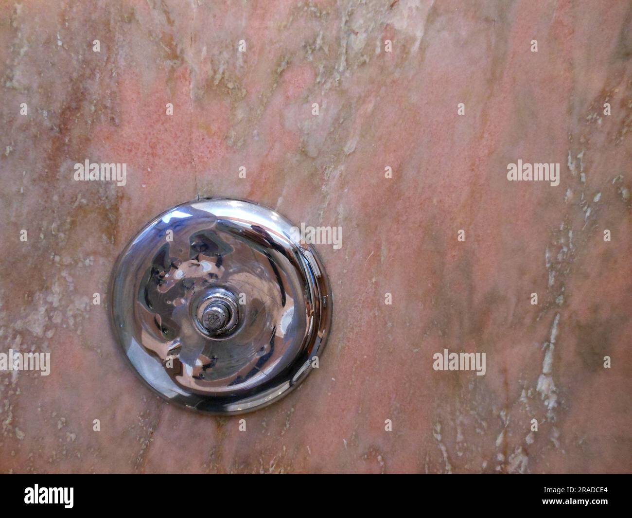 Silver round object on salmon colored marble background Stock Photo