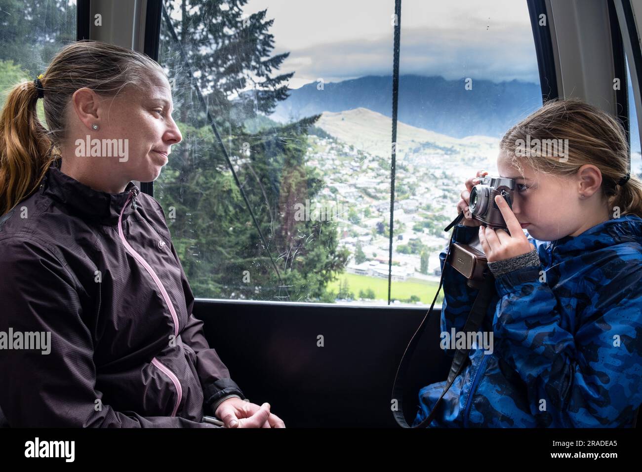 A mother and daughter take pictures in the cablecar up to Skyline Resort on Bob's Peak in Queenstown, New Zealand. Photo: Rob Watkins Stock Photo