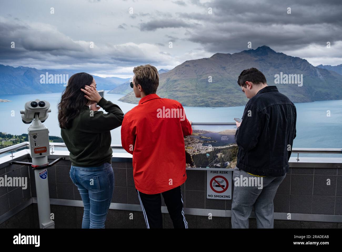 Tourists take mobile phone pictures at the Skyline Resort on Bob's Peak above Queenstown and Lake Wakatipu in New Zealand. Photo: Rob Watkins Stock Photo