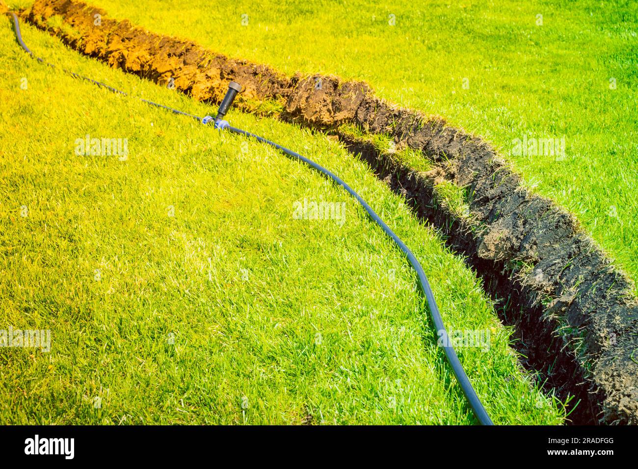 Self-installation of irrigation with a retractable sprinkler in the finished lawn. Laying water pipes with sprayers under the lawn for irrigation. Stock Photo