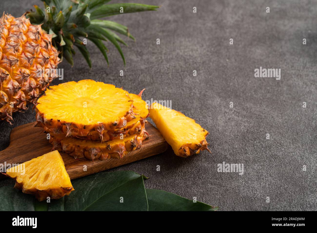 Fresh cut sliced juicy pineapple in a plate over dark gray table background. Stock Photo