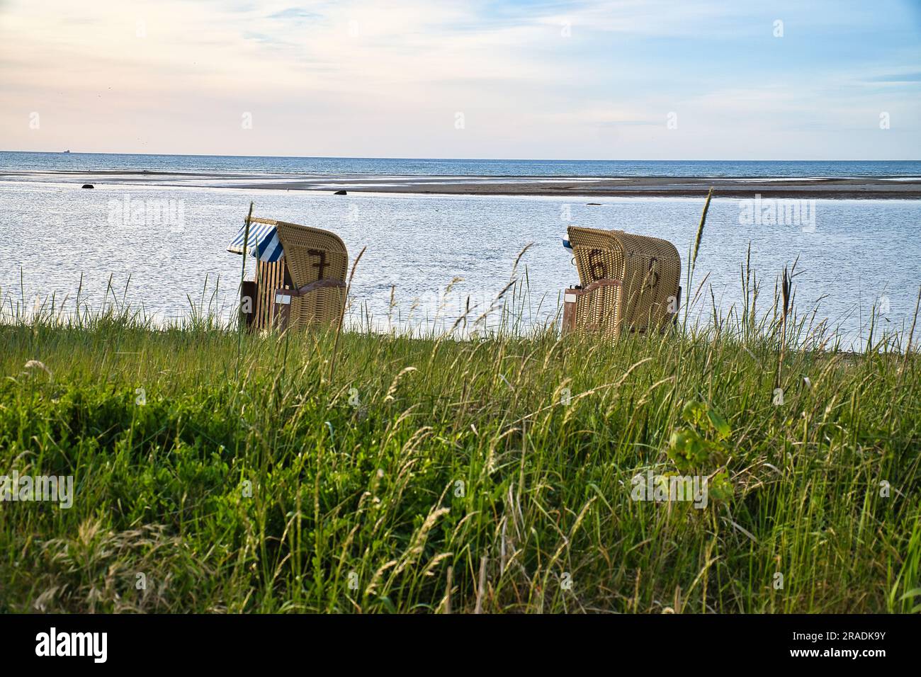 Beach chair in the sand in front of the Baltic Sea on the island of Poel at sunset. Dune grass by the sea. Landscape shot from the coast Stock Photo