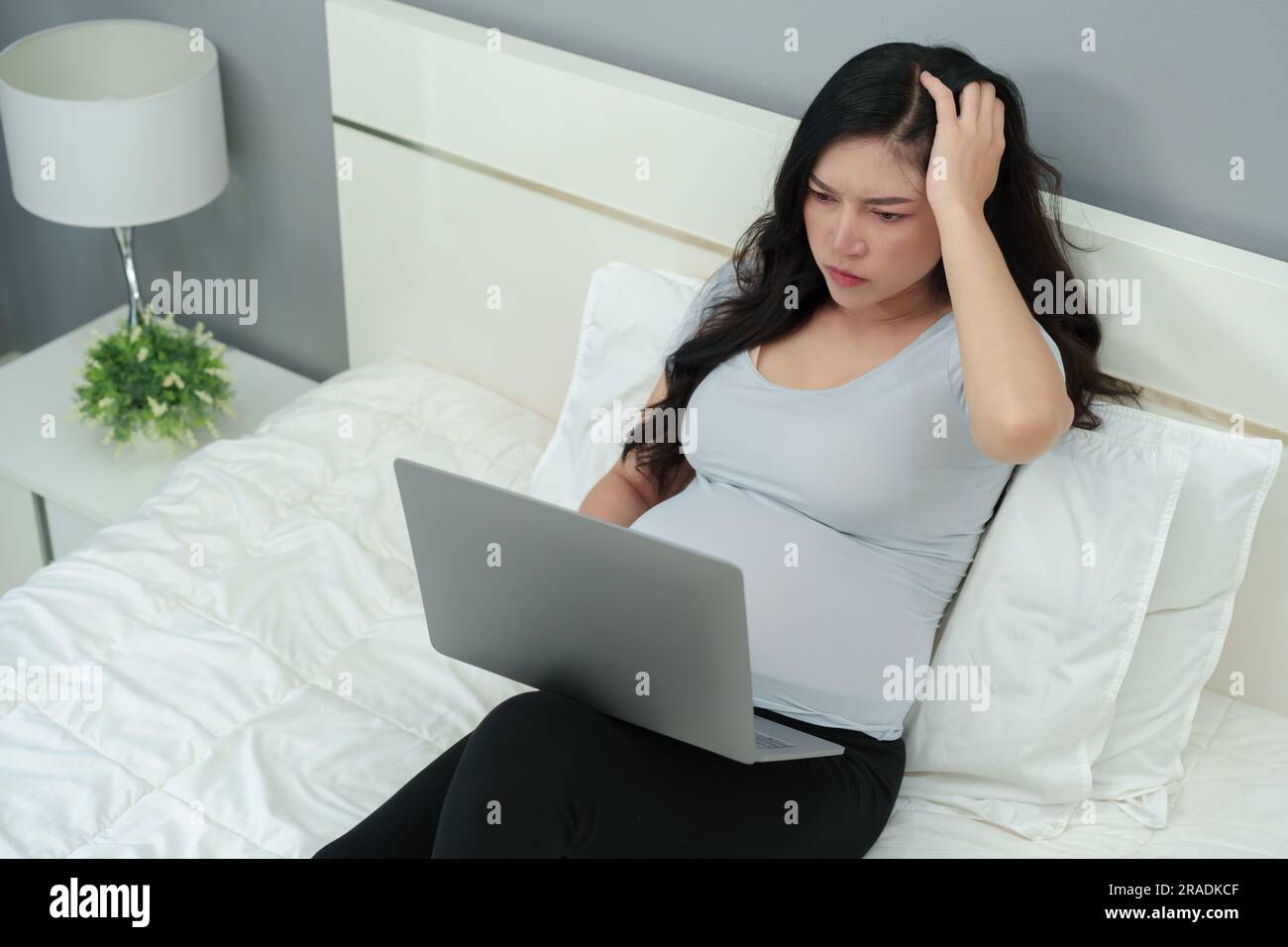 stessed pregnant woman working with laptop computer on a bed Stock Photo Alamy