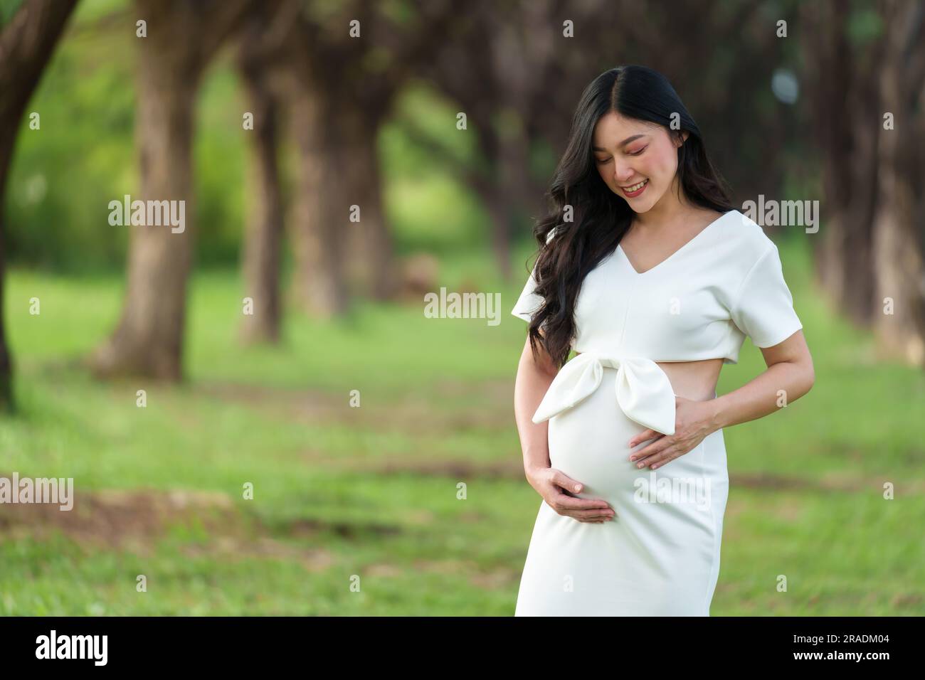 pregnant woman standing and looking her belly in the park Stock Photo ...
