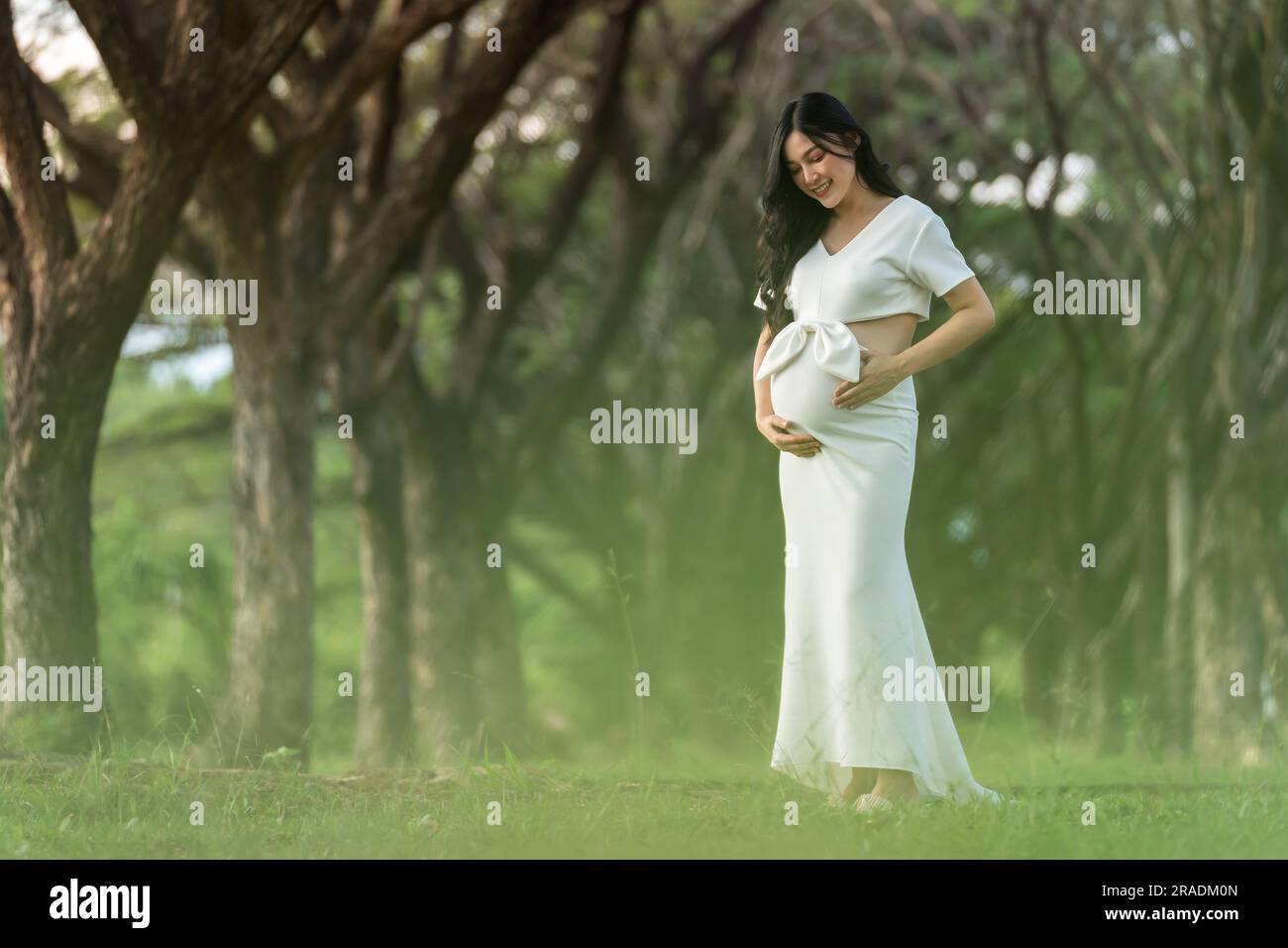 pregnant woman standing and looking her belly in the park Stock Photo ...