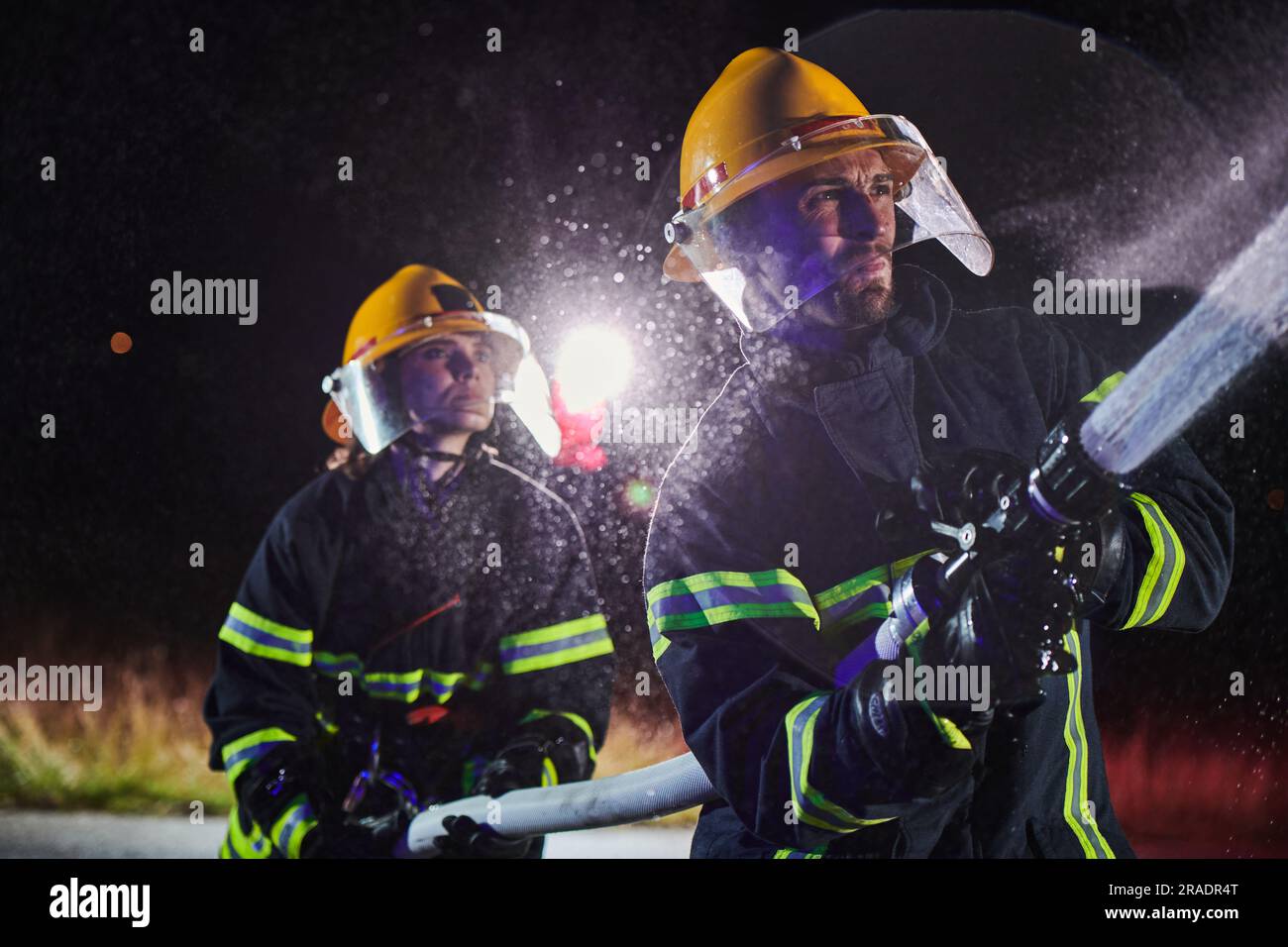 Firefighters using a water hose to eliminate a fire hazard. Team of ...