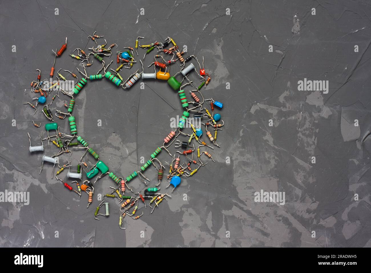 Heart shape made from electronic components on gray concrete background. Symbol of love from resistors and capacitors. Happy Valentines Day greeting c Stock Photo