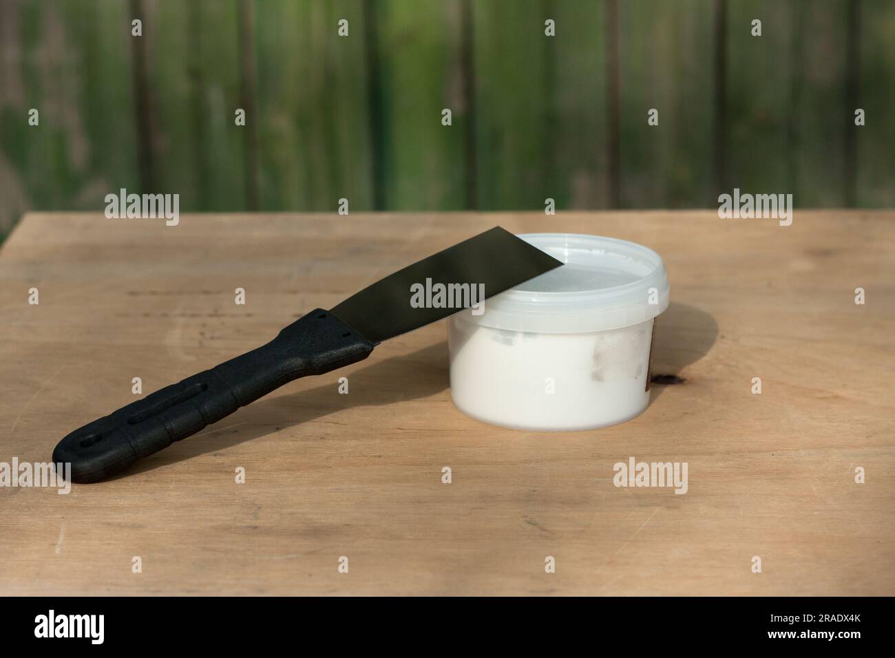 construction trowel and can of white putty on plywood surface. Still