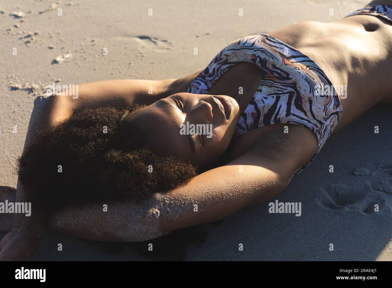 Happy african american woman in bikini sunbathing on sunny beach Stock Photo