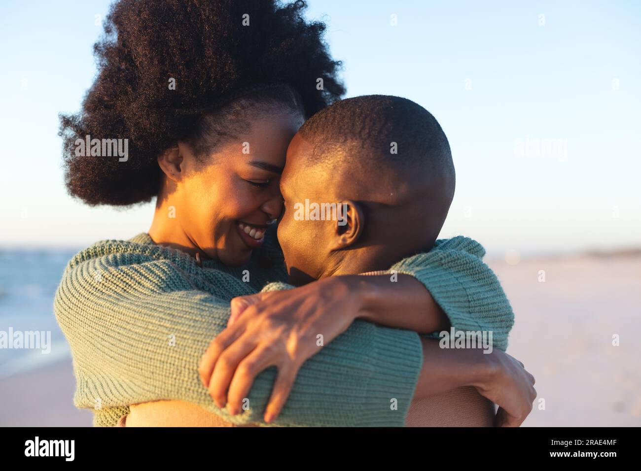 Happy african american couple embracing and smiling on sunny beach ...