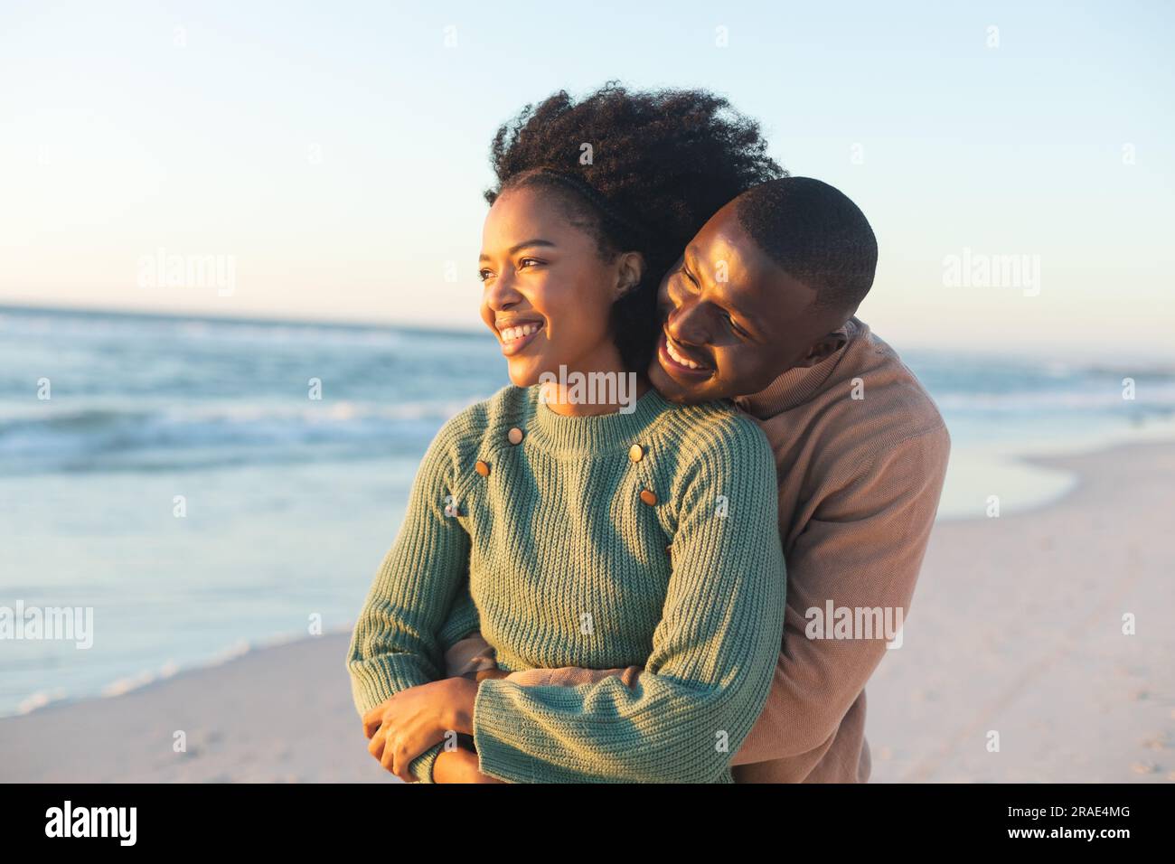 Happy african american couple embracing and smiling on sunny beach ...