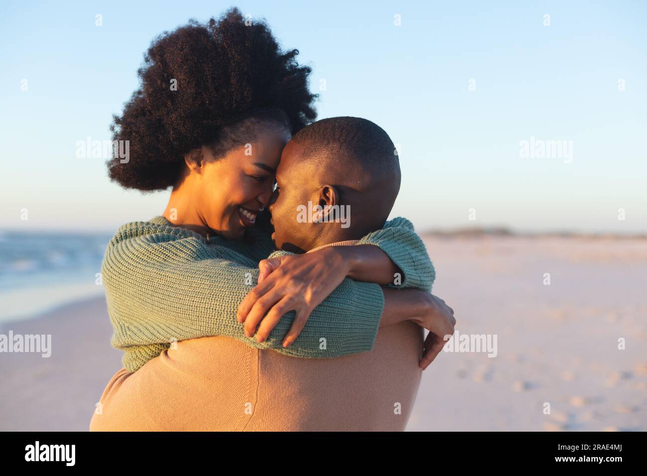 Happy african american couple embracing and smiling on sunny beach ...