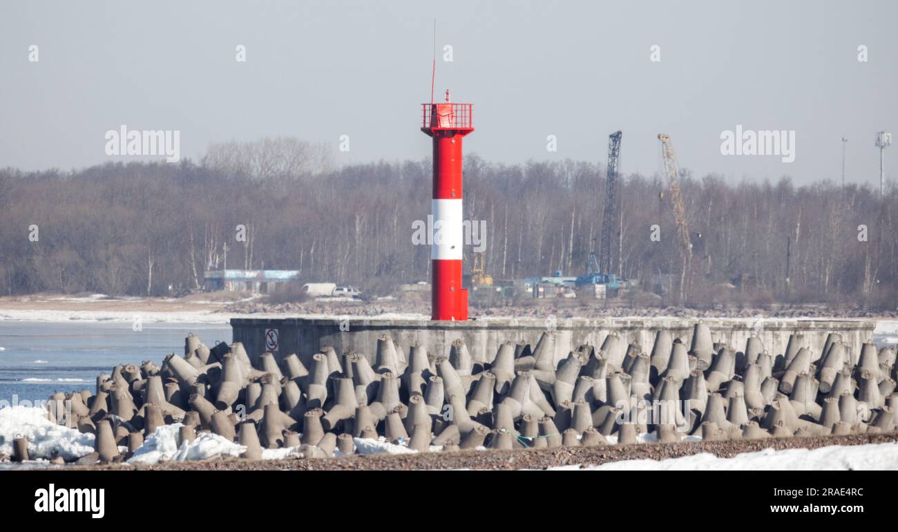 Coastal navigation mark is on a breakwater end, striped red white lighthouse tower Stock Photo