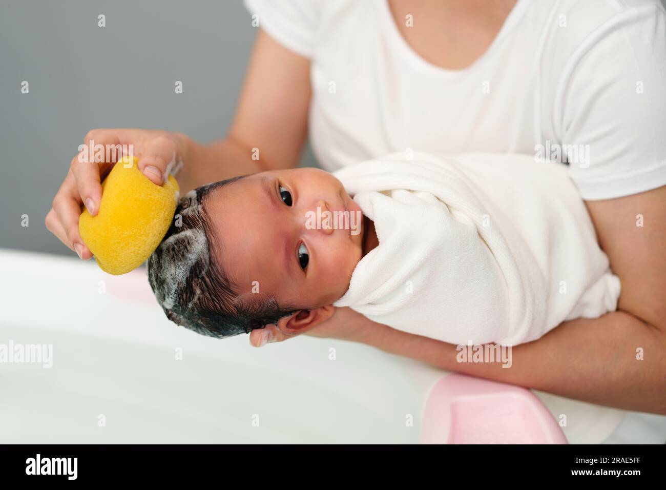 mother is washing newborn baby hair with sponge in a bathtub Stock Photo Alamy