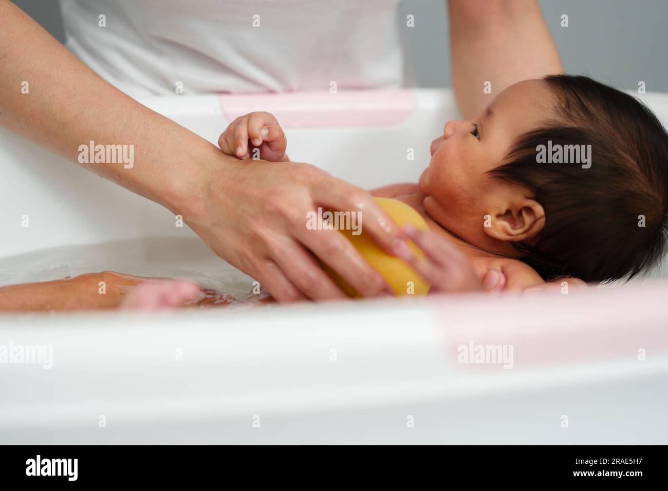 mother give a bath newborn baby in a bathtub Stock Photo Alamy