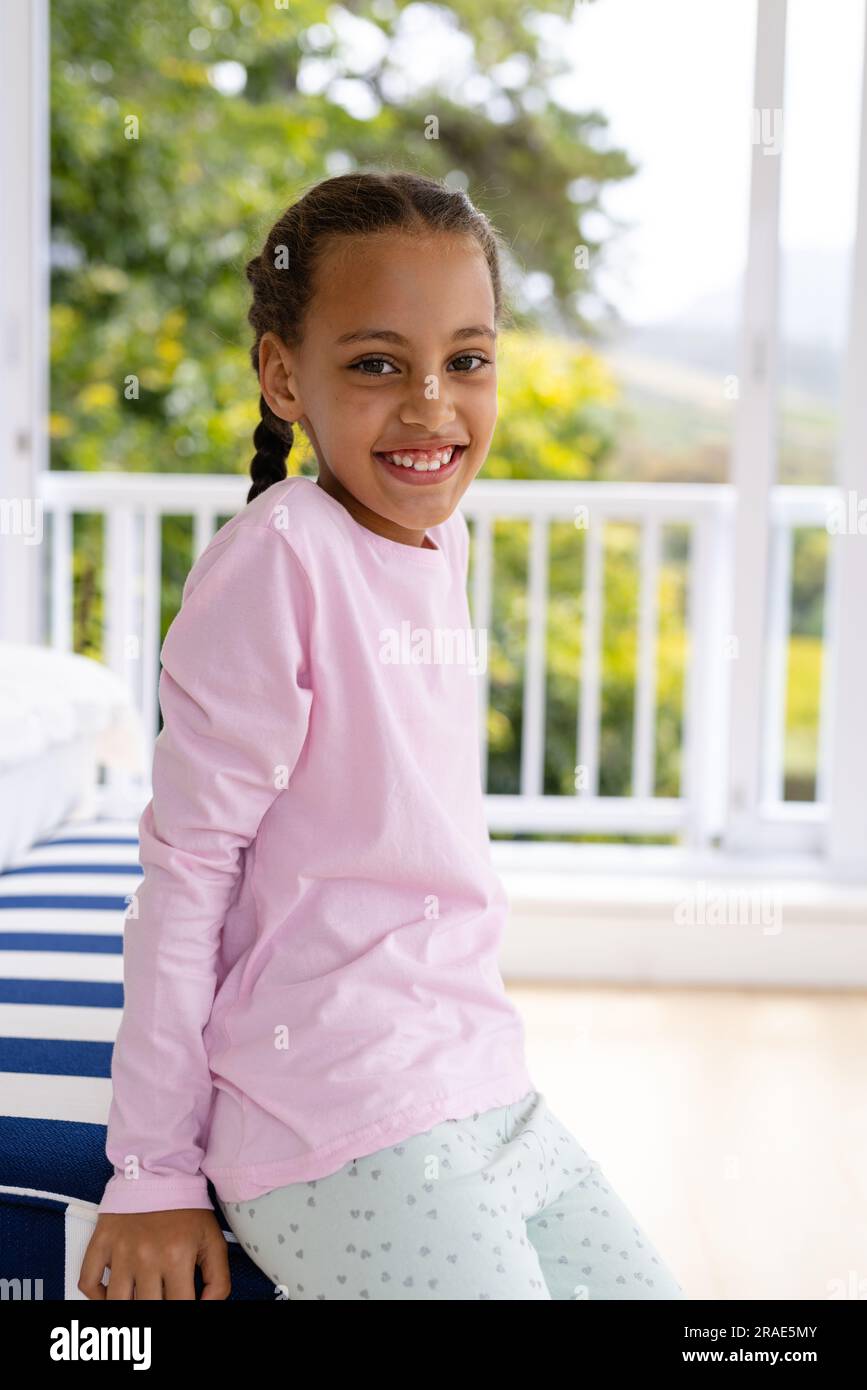 Portrait of happy biracial girl wearing pyjamas in bedroom in