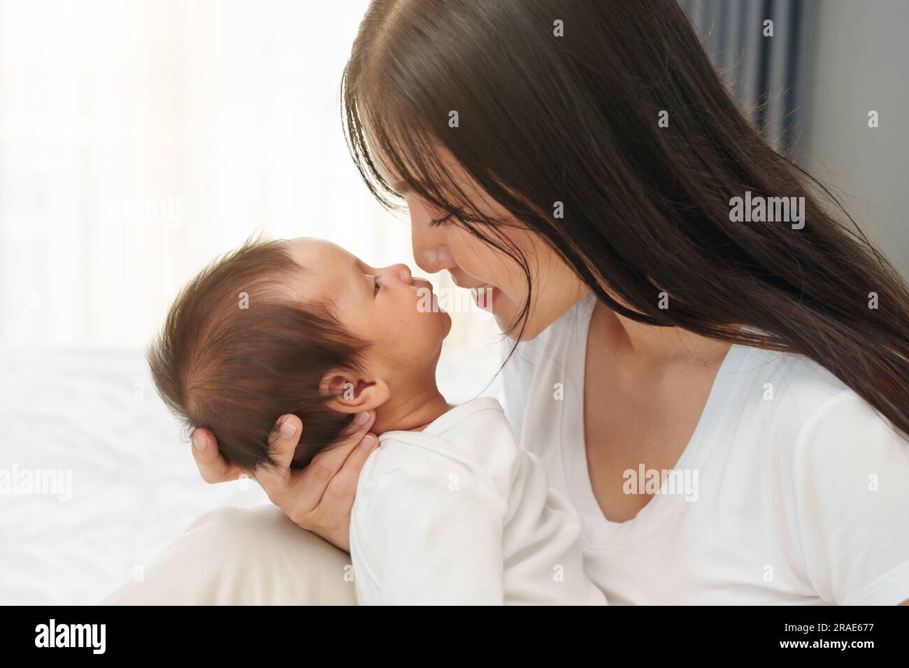 mother kissing her newborn baby on a bed Stock Photo Alamy
