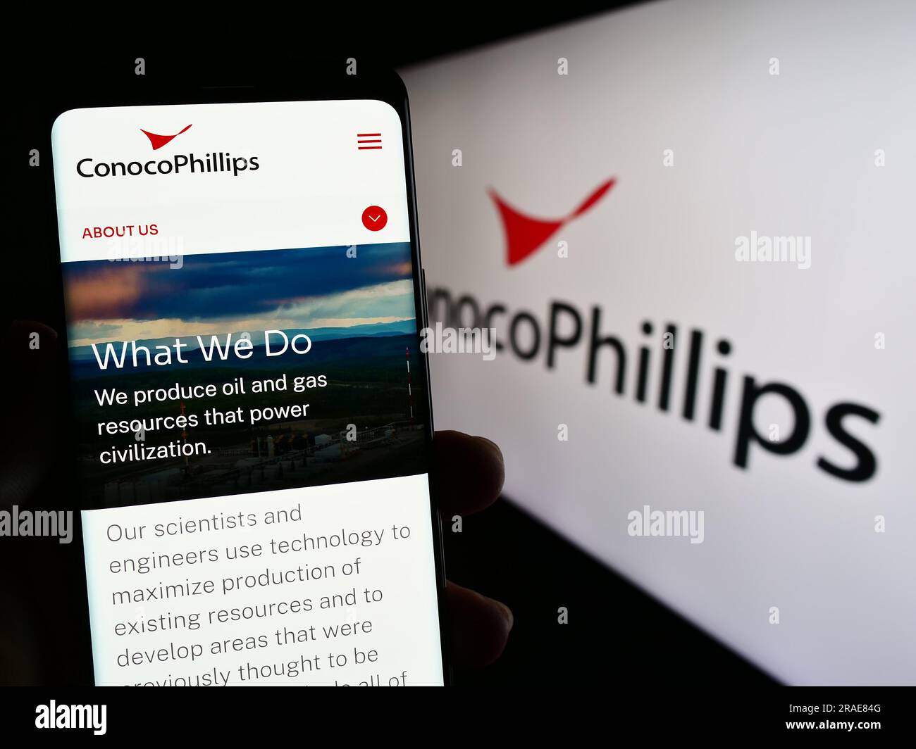 Person holding smartphone with webpage of US oil and gas business ConocoPhillips Company on screen with logo. Focus on center of phone display. Stock Photo