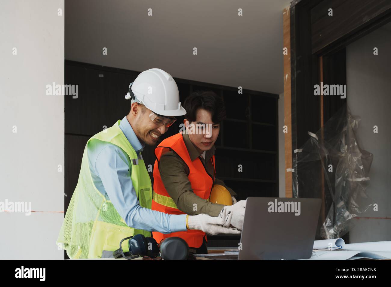 multi ethnic engineer brainstorming and measuring for cost estimating on blueprint and floor