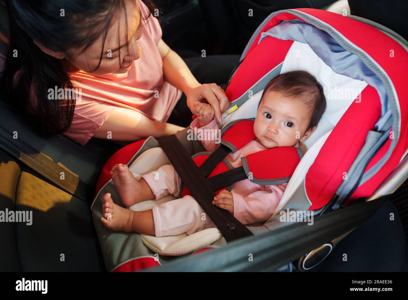 mother take care her newborn baby in the car seat. play and talking