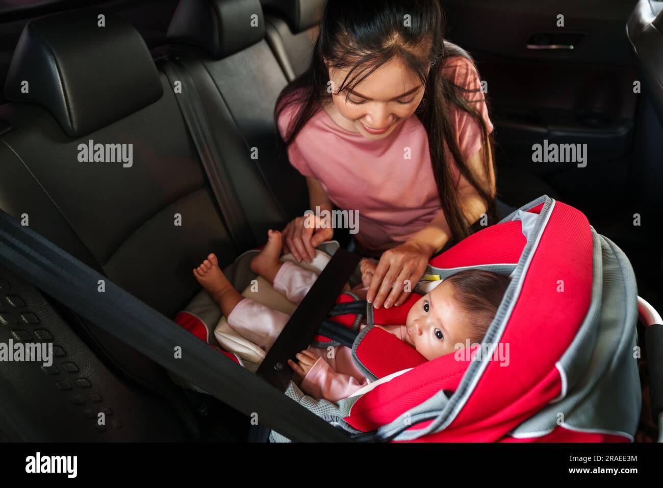 mother take care her newborn baby in the car seat. play and talking