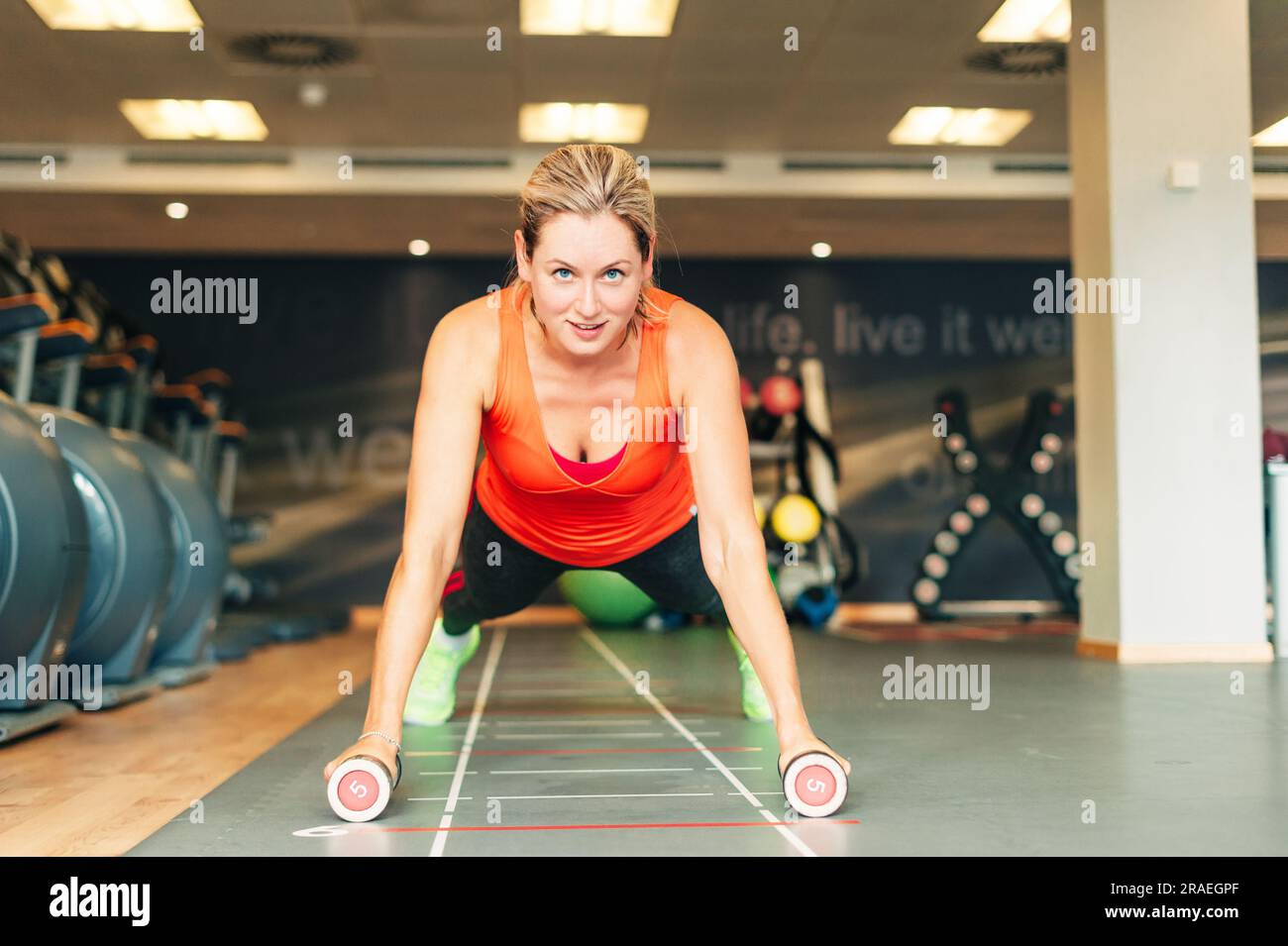 Young fit woman working in gym club, planks with dumbbells, sport lifestyle Stock Photo