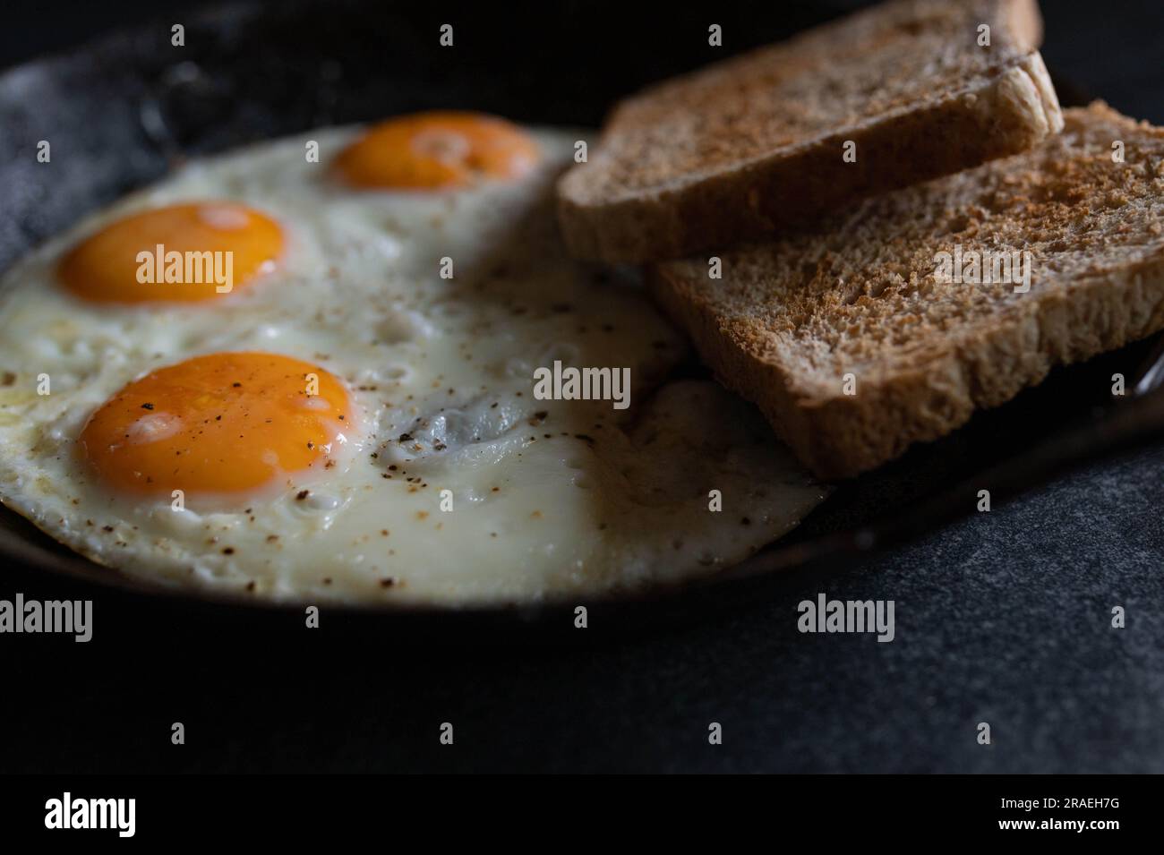 Fried eggs with toast in a cast iron pan Stock Photo