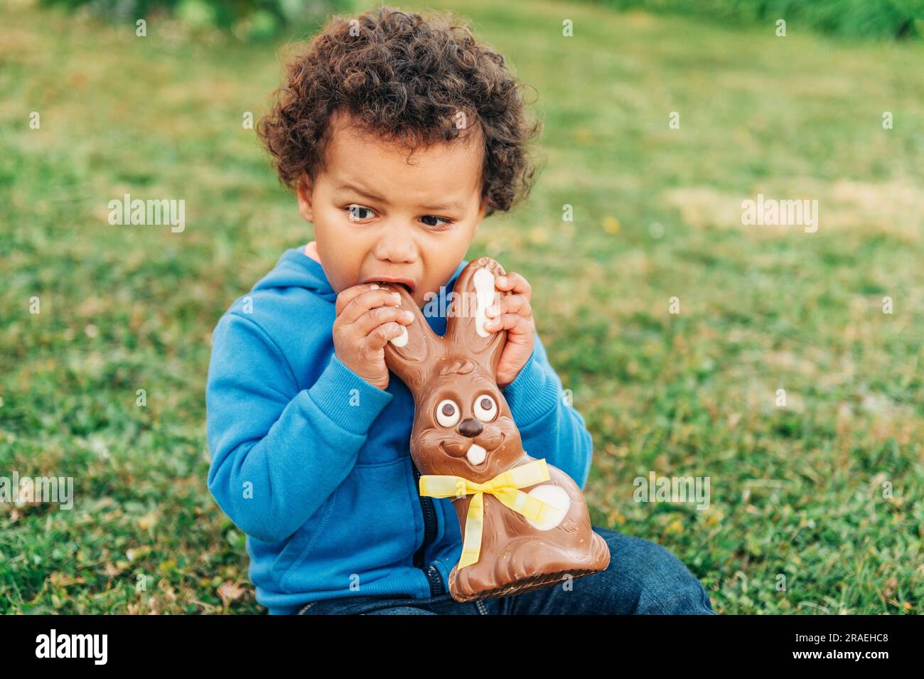 Adorable two year old african toddler boy eating chocolate bunny on ...