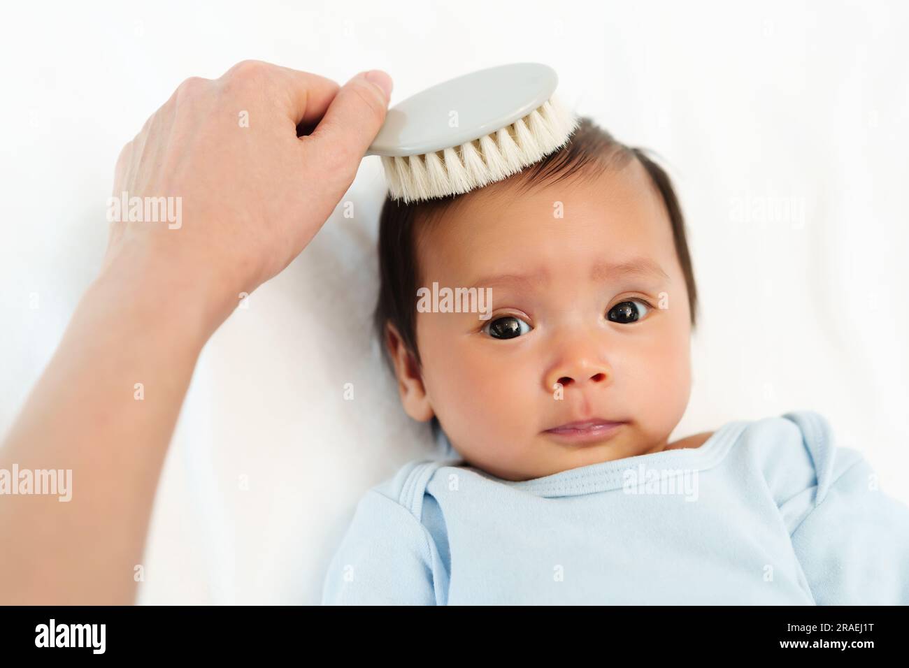 mother combing her newborn baby hair on a bed Stock Photo